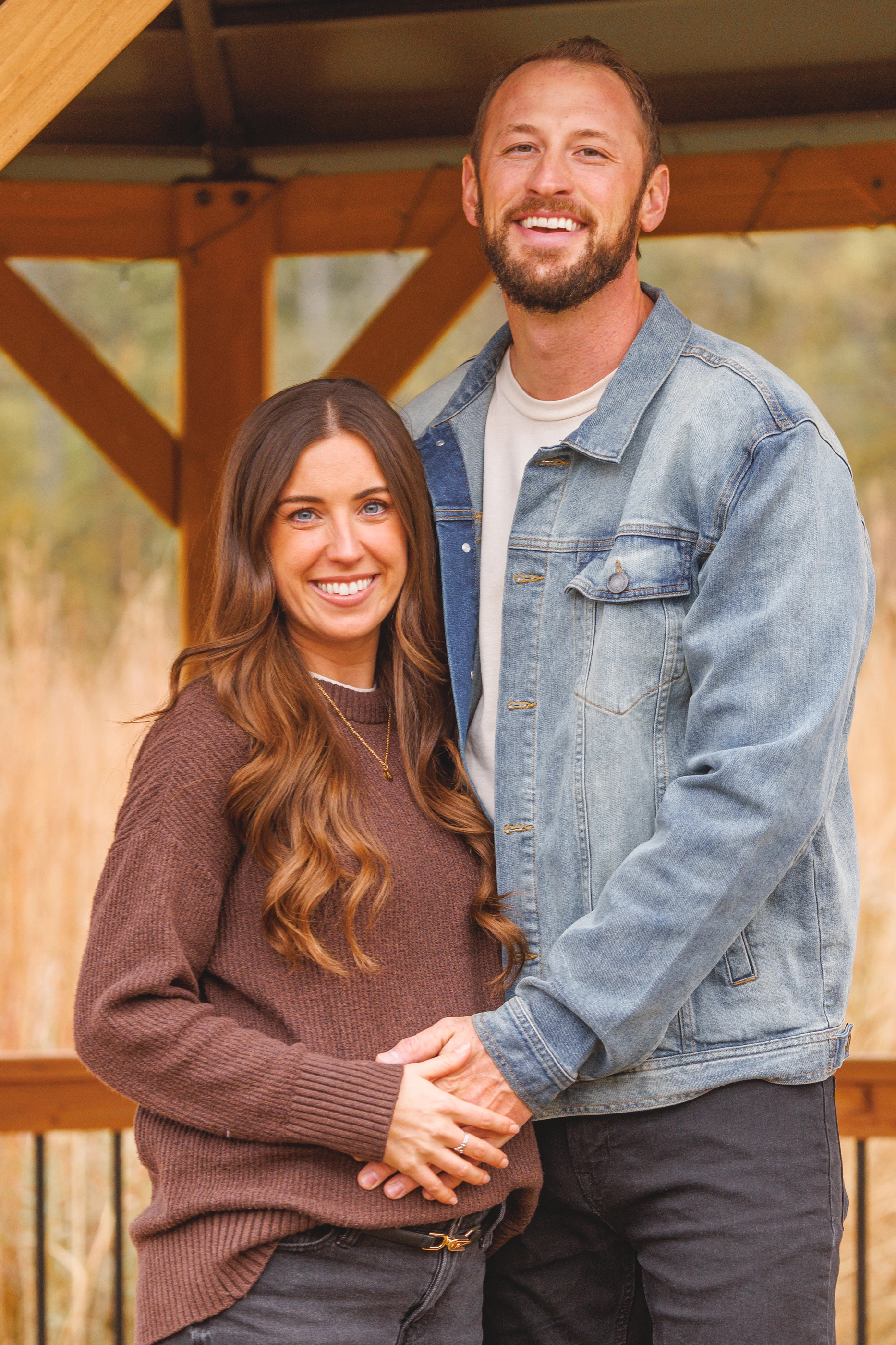 Couple smiling together beneath a wooden shelter